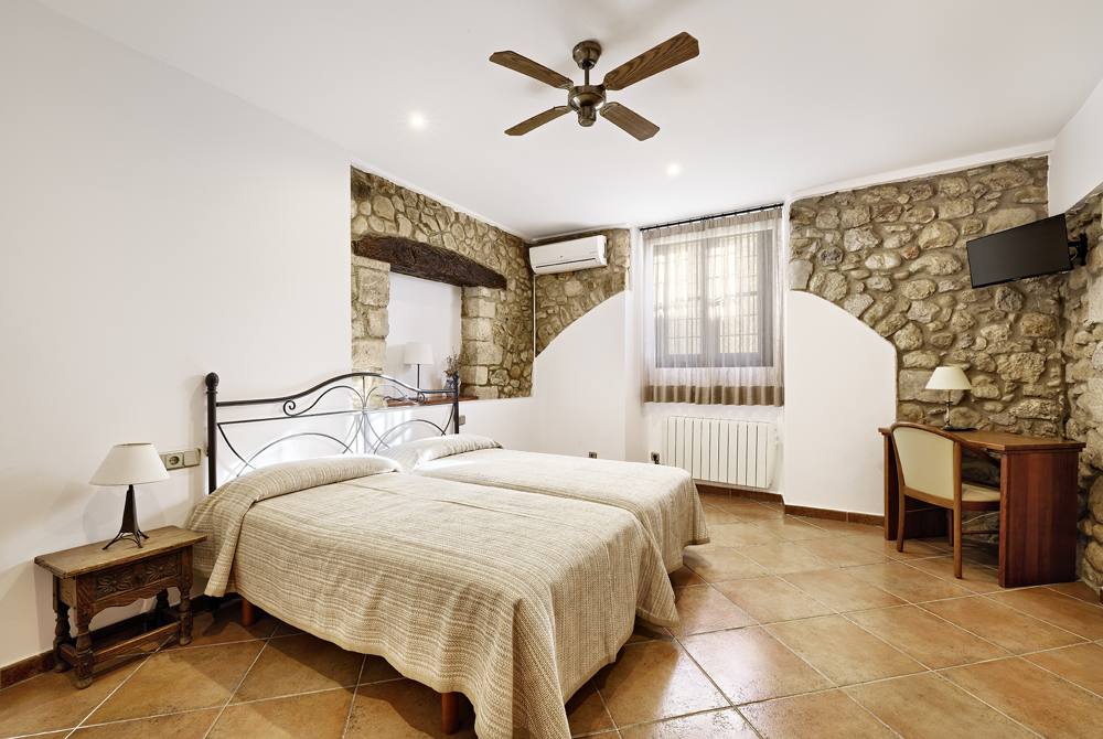 Habitació de dos llits amb paret de pedra