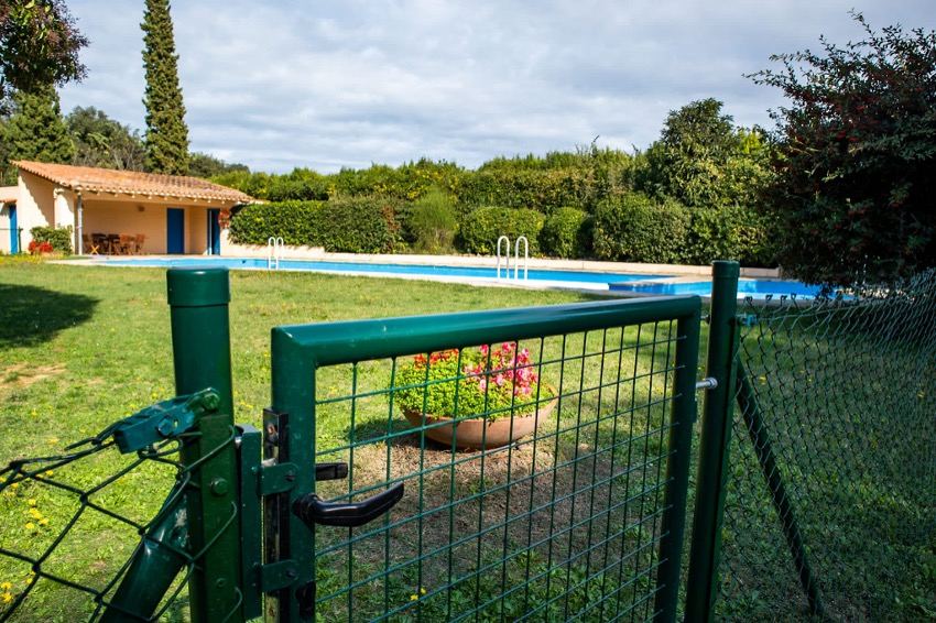 Piscina de Mas Jonquer amb la tanca de protecció i la caseta de serveis